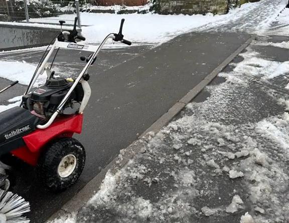 Professionelle Kehrmaschine im Winterdienst in Stuttgart räumt Gehweg und Zufahrt komplett von Schnee und Matsch.